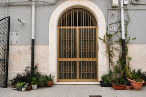 L'ingresso di un edificio con un'ampia porta ad arco, piante in vaso e un cartello numerico.