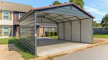 Ein Metall-Carport mit Satteldach, neben einem Wohngebäude.