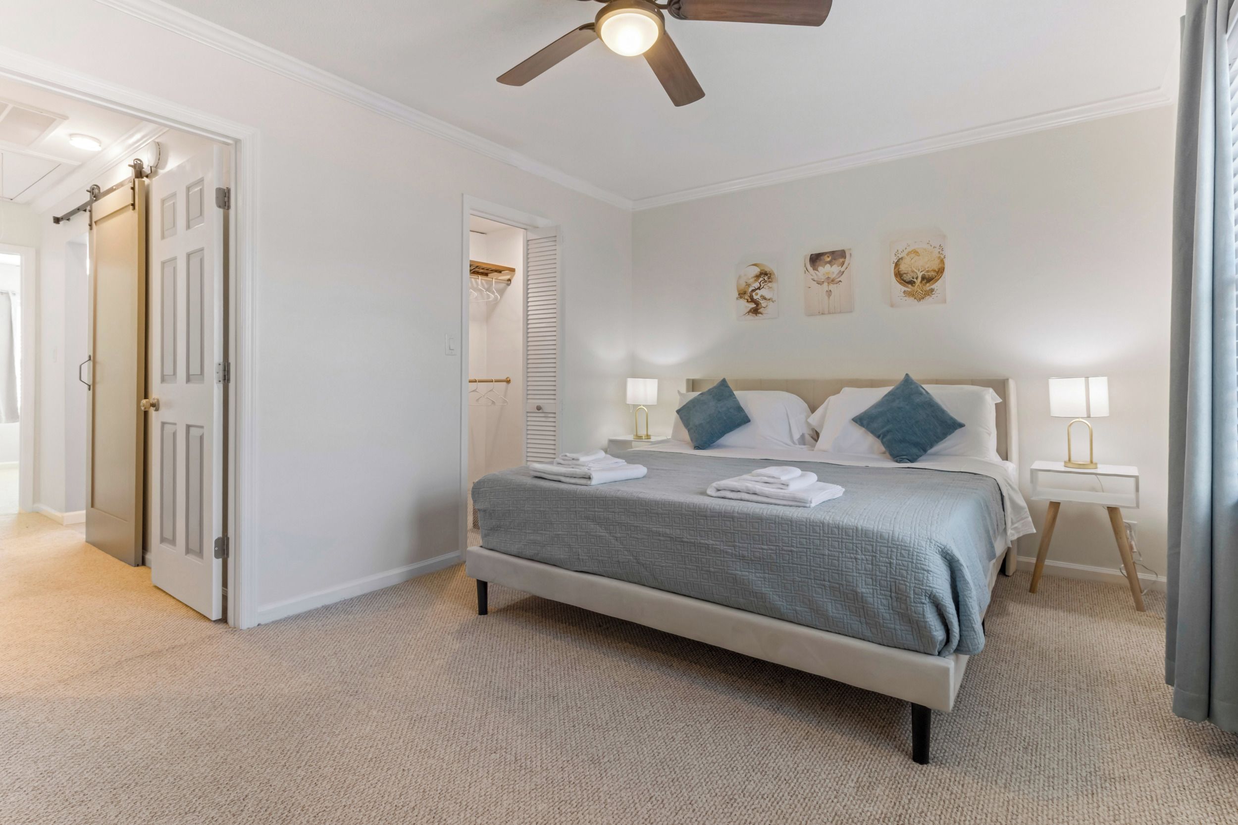 Ein Schlafzimmer mit Bett, Nachttischen, Deckenventilator und Bildern an der Wand.