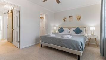 Ein Schlafzimmer mit Bett, Nachttischen, Deckenventilator und Bildern an der Wand.