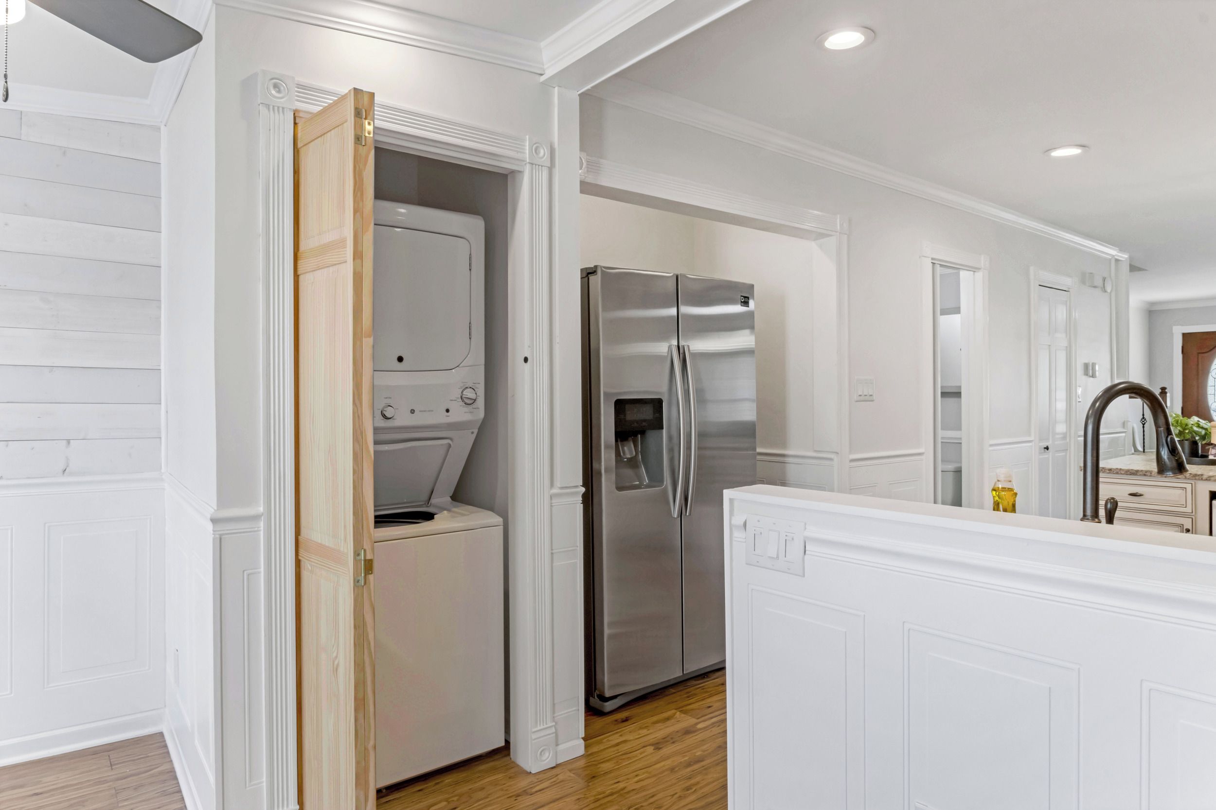A modern kitchen with white cabinetry, a stainless steel refrigerator, and a built-in washing machine.