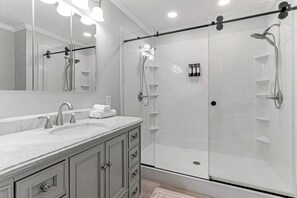 Un baño moderno con un espejo grande, un lavamanos y una ducha a ras de suelo.