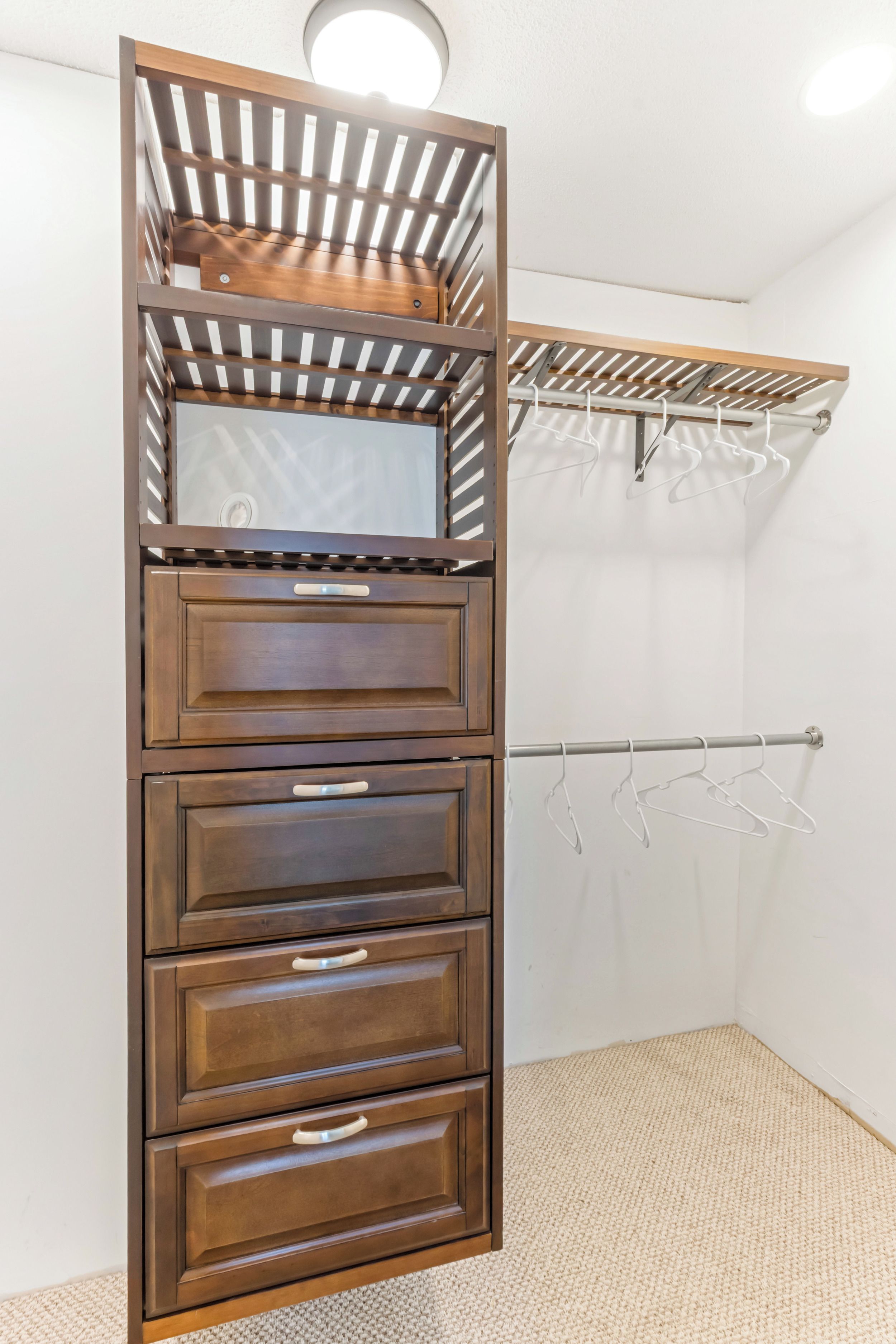 Ein Eckschrank mit Holztüren, einer Kleiderstange und einem Spiegel.