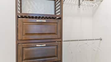Ein Eckschrank mit Holztüren, einer Kleiderstange und einem Spiegel.