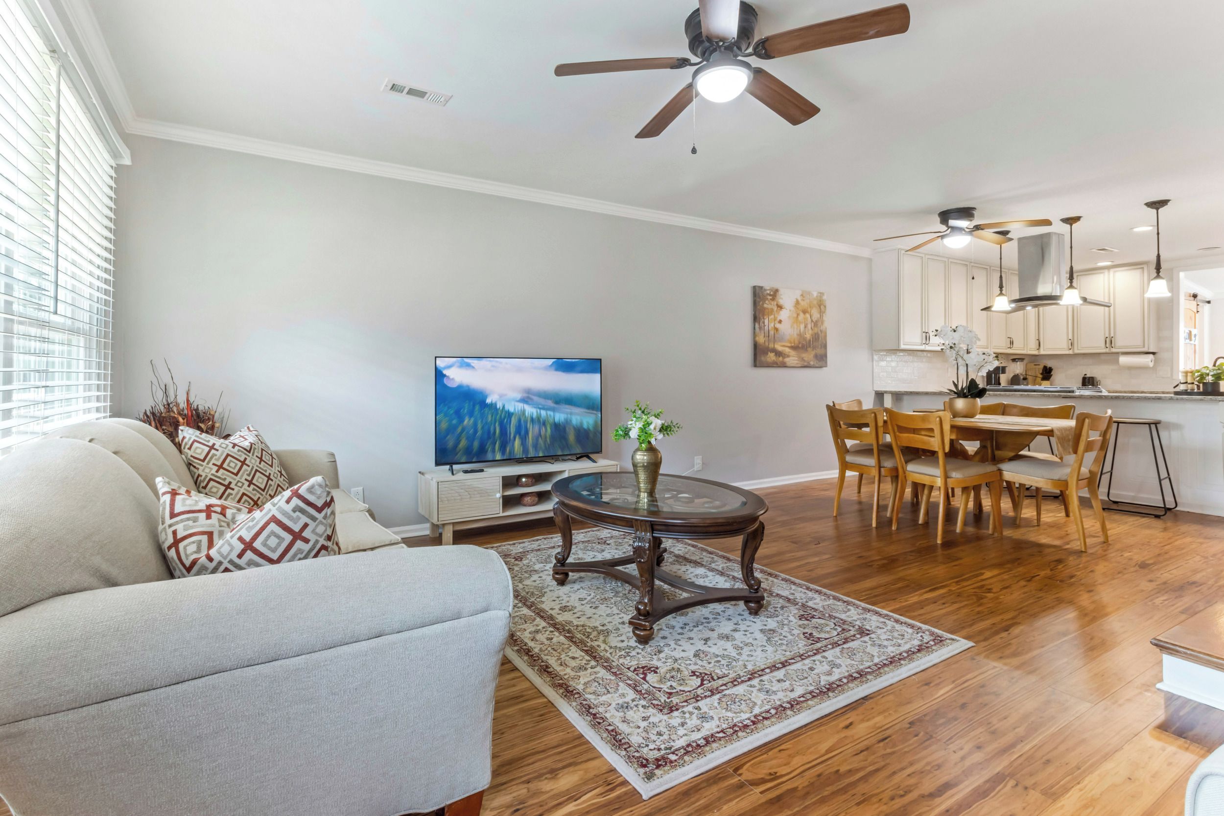 A living room with a sofa, TV, and a dining area with chairs and a table.