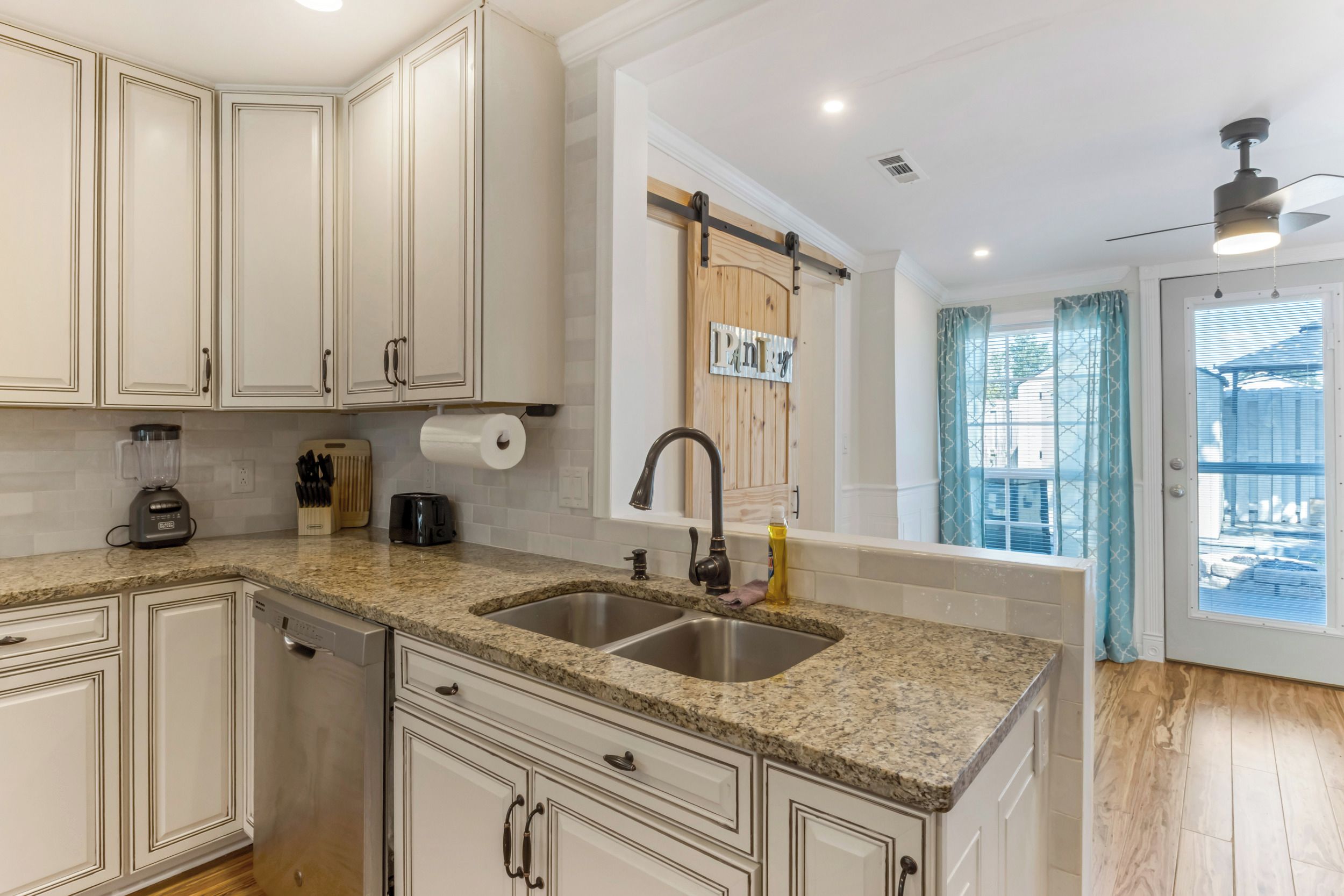 A kitchen with granite countertops, stainless steel sink, and white cabinetry.