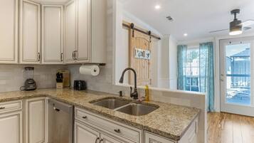 A kitchen with granite countertops, stainless steel sink, and white cabinetry.