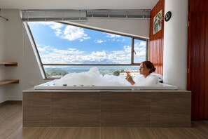 Una persona relajándose en una bañera con vistas al cielo y al paisaje.