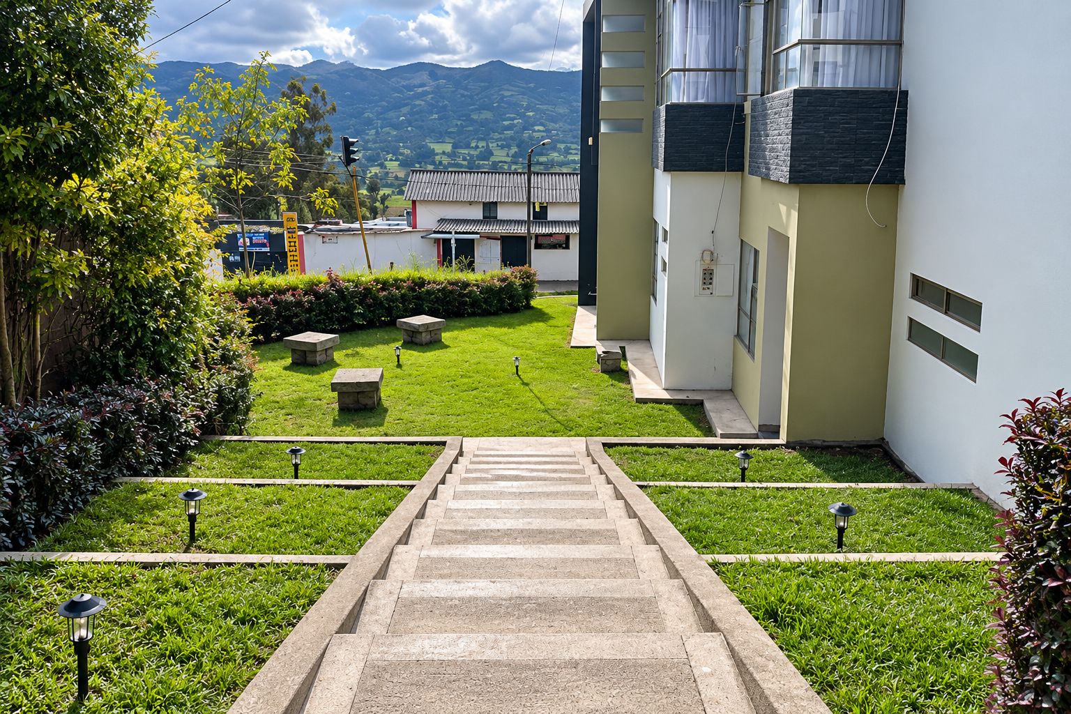 Un chemin mène à un bâtiment à l’architecture moderne, entouré d’un jardin bien entretenu avec de la pelouse et des arbustes.