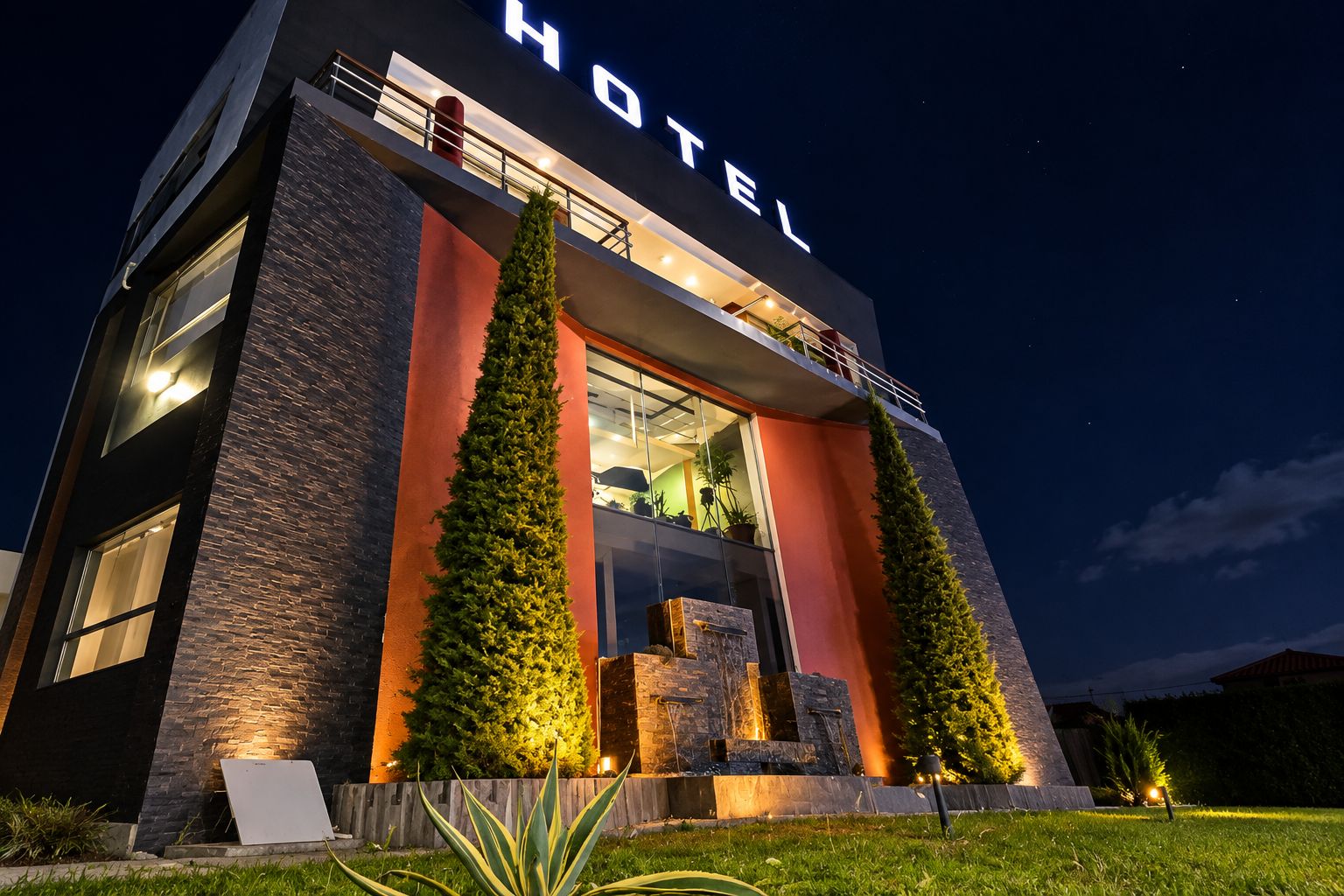 Un hotel moderno con un cartello ben visibile con la scritta 'HOTEL', ampie finestre e un ingresso luminoso.