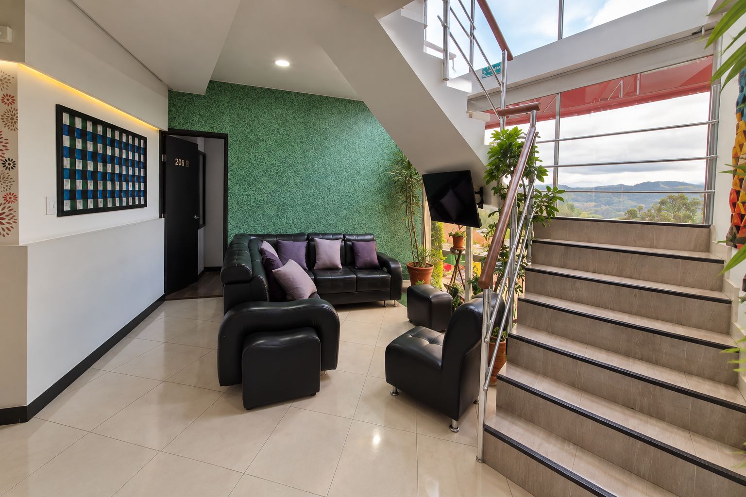 A modern interior with a staircase, a sofa set, and a green textured wall.