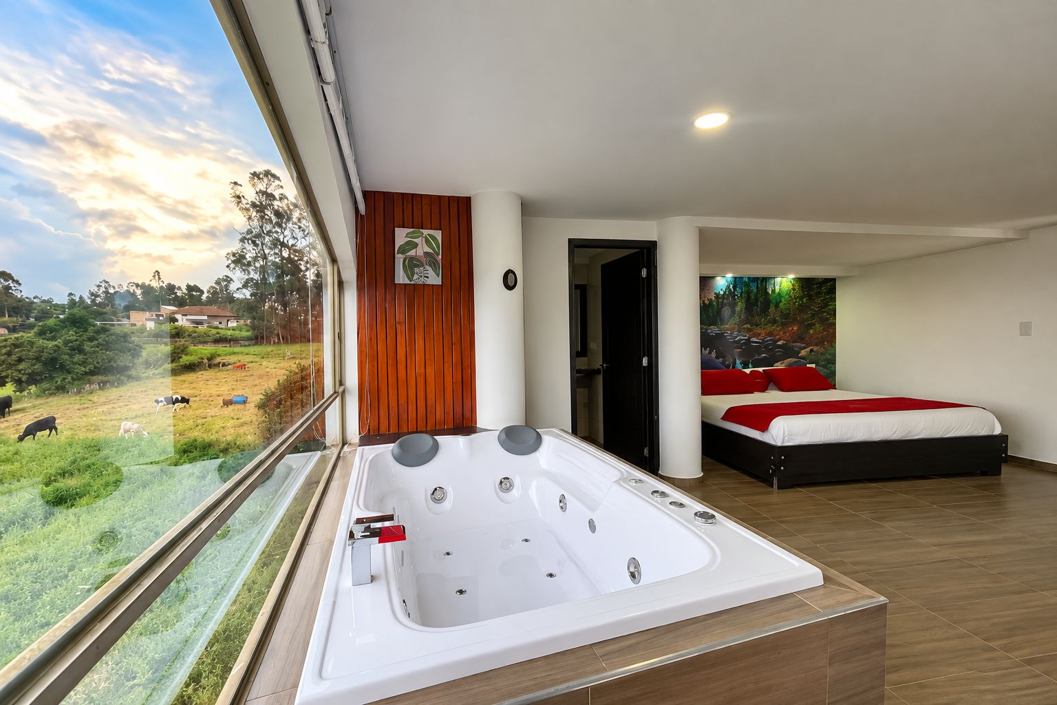 A modern bedroom with a large bed, a jacuzzi, and a view of a green landscape.