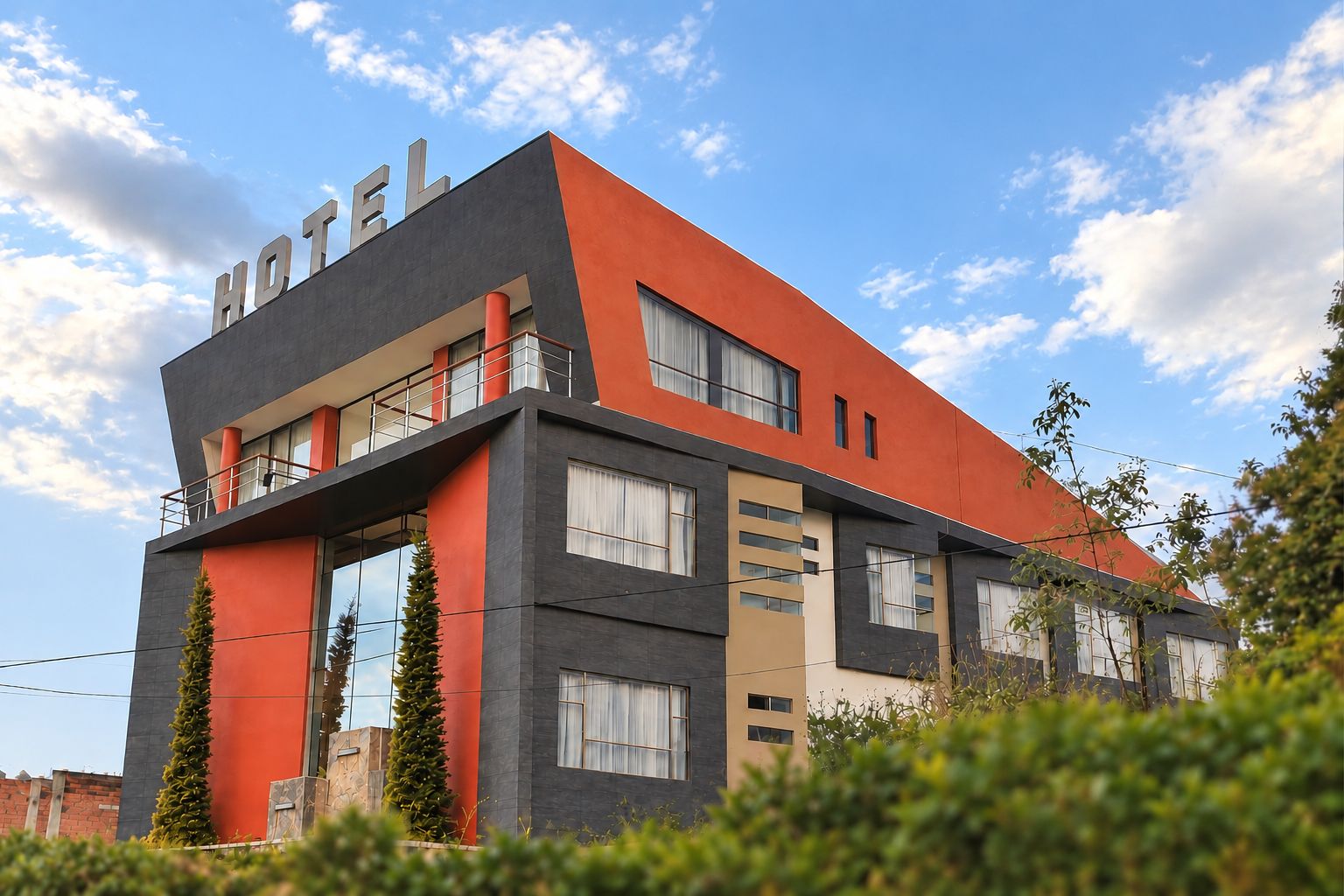 Un hotel moderno con techo plano, ventanas grandes y un llamativo letrero que dice 'HOTEL'.