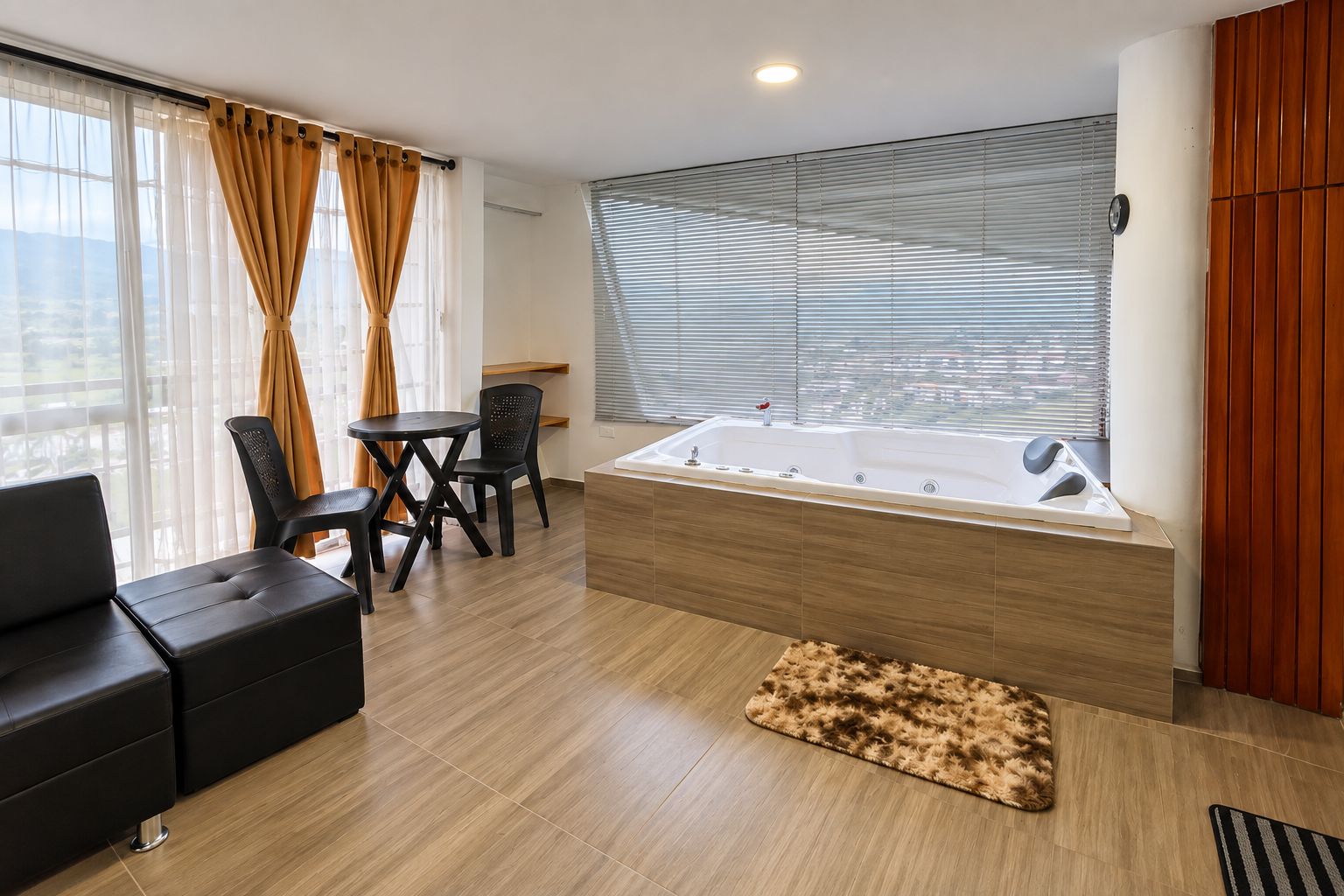 Quarto moderno com sofá, mesa, cadeiras, uma janela grande com persianas e uma banheira.