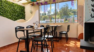 Una cafetería con un muro curvo, una pared verde y vistas a una zona residencial.