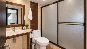 Un baño moderno con lavamanos, inodoro y cabina de ducha.