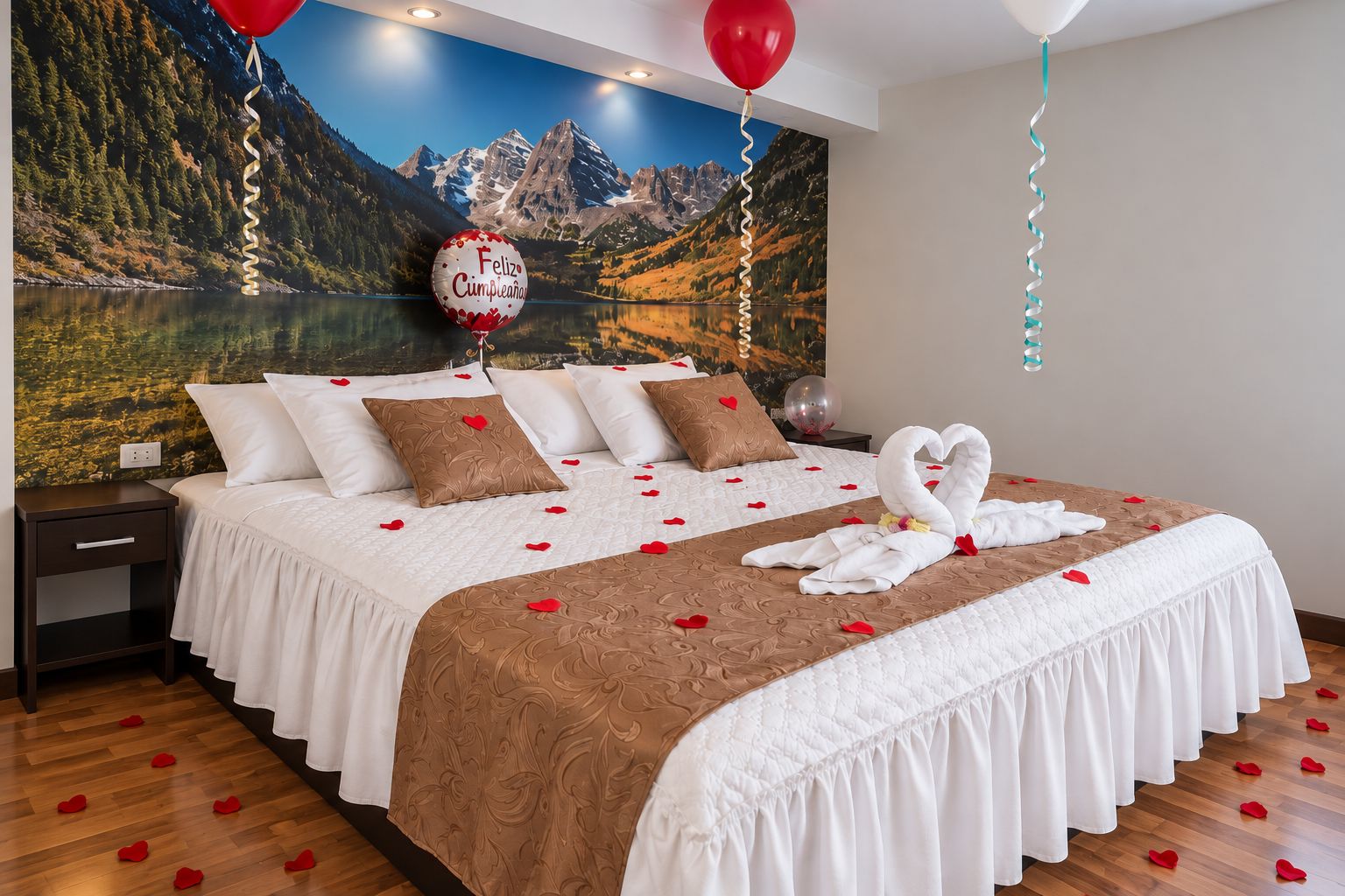 A hotel room with a bed, pillows, a swan-shaped towel arrangement, and a scenic mountain view.