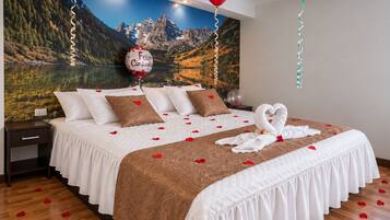 A hotel room with a bed, pillows, a swan-shaped towel arrangement, and a scenic mountain view.