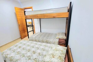 A room with two bunk beds, a wooden door, and a small table. - Au cœur de la MARSA (Marsa)