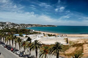 A coastal cityscape with a beach, palm trees, and buildings. - Au cœur de la MARSA (Marsa)