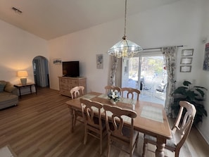 A dining area with a wooden table and chairs, a television on a dresser, and a view through a glass door to an outdoor patio. - 4 bedroom accommodation in Kissimmee (Kissimmee)