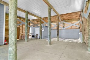 An interior space with a high ceiling supported by wooden beams, a concrete floor, and a grey wall. - Summer Salt (Port St. Joe)
