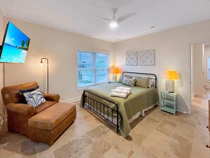 A bedroom with a bed, a chair, a TV, and a ceiling fan. - Summer Salt (Port St. Joe)
