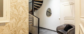 Ein modernes Interieur mit einer Wendeltreppe, einem runden Spiegel und einem bequemen Sessel.