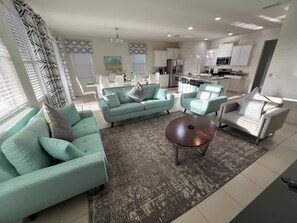A modern living room with teal sofas, a coffee table, and a kitchen in the background. - Poolside Paradise!

Poolside Paradise! (Davenport)