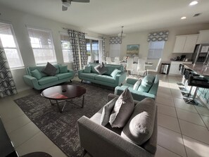 A modern living room with teal sofas, a coffee table, and a dining area with white chairs. - Poolside Paradise!

Poolside Paradise! (Davenport)