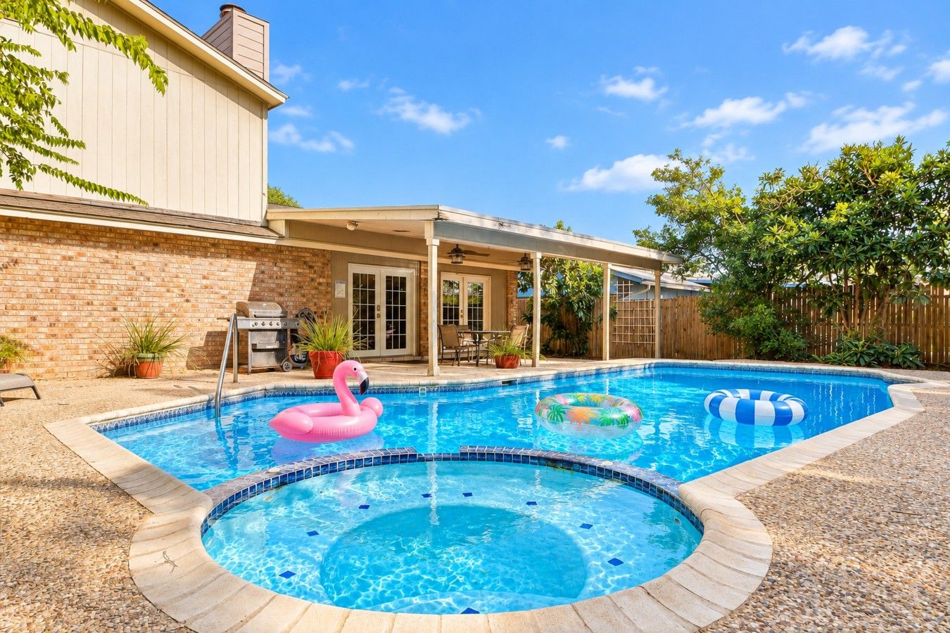 A backyard with a swimming pool, a barbecue grill, and a covered patio area.