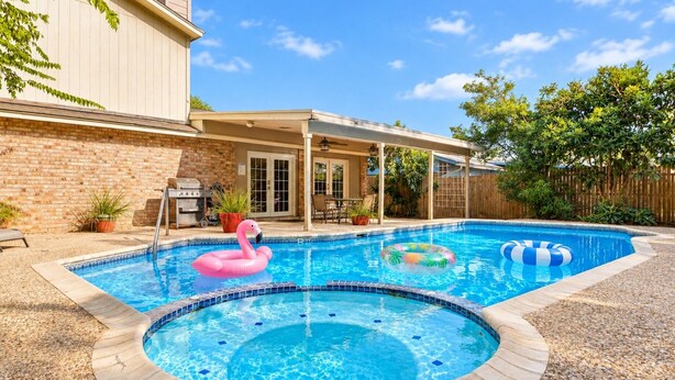 Un jardin avec une piscine, un barbecue et un espace patio couvert.