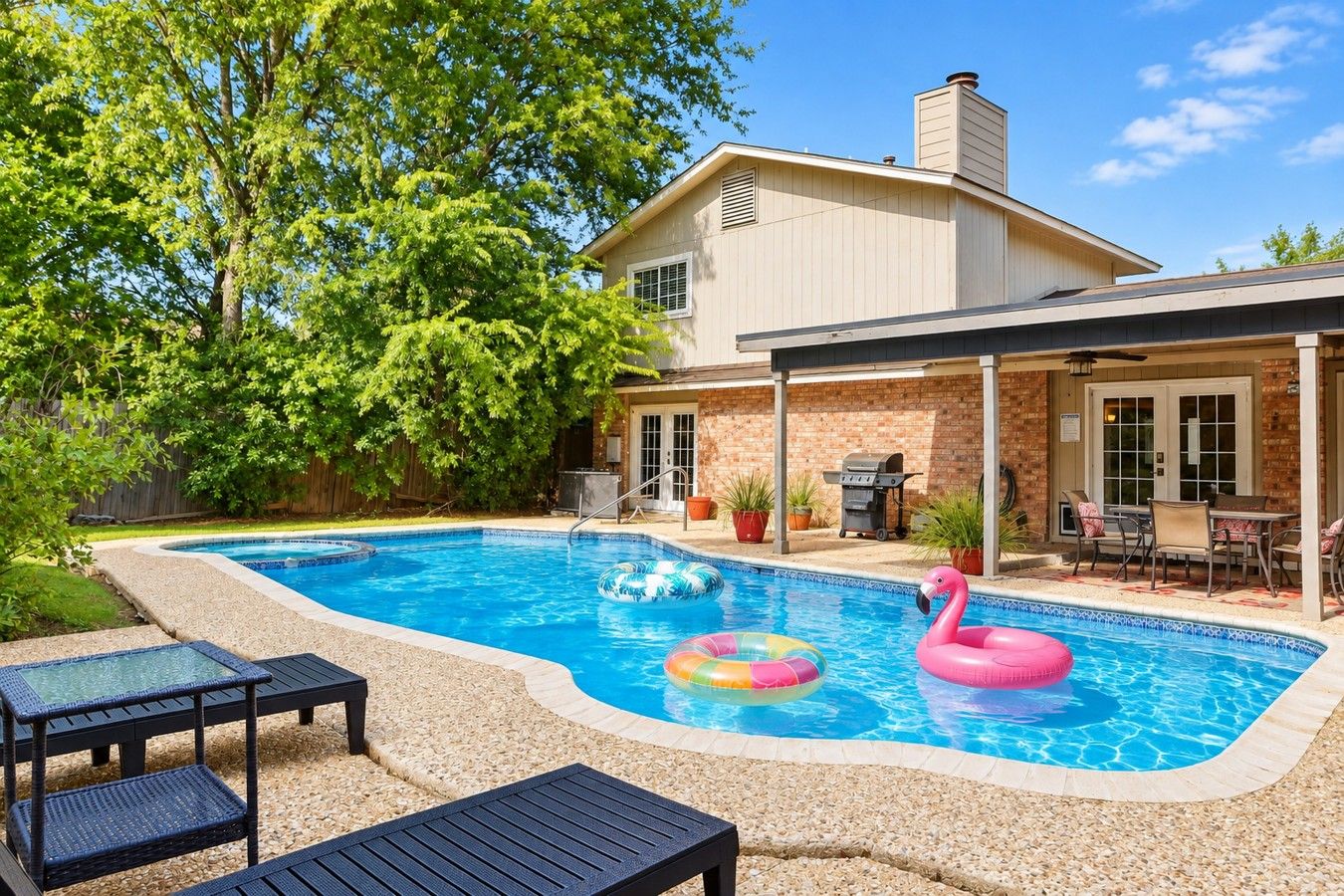 Un jardin avec une piscine, des chaises longues et un espace barbecue.
