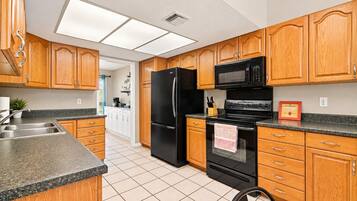 Una cocina con armarios de madera, un refrigerador negro, un microondas y una estufa.