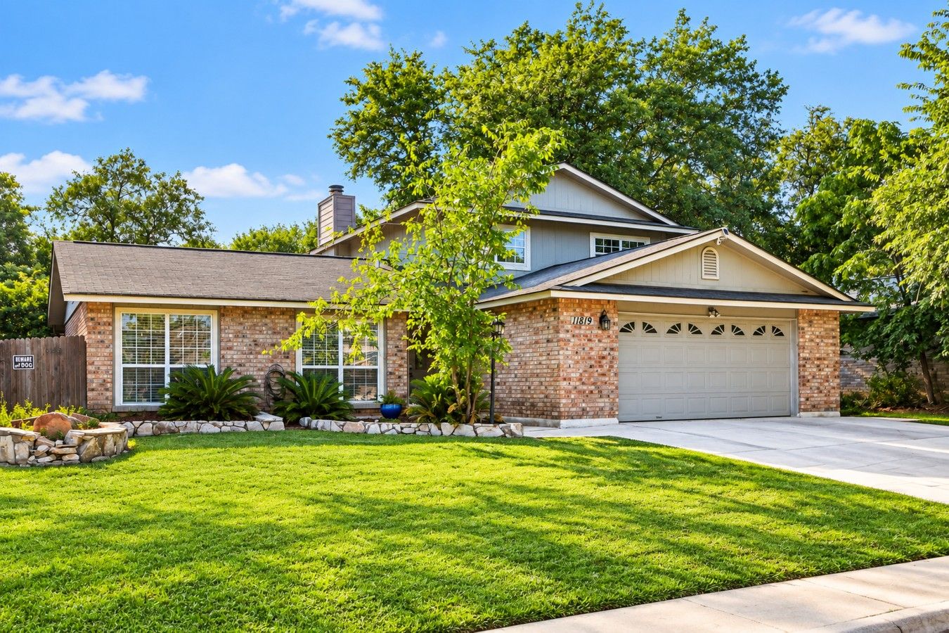 A two-story house with a brick facade, a garage, and a well-maintained lawn.
