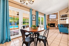 A spacious living area with a dining table, chairs, a sofa, and a fireplace. - Swim by Day~Soak by Night~Fenced Yard~Poolside BBQ (San Antonio)