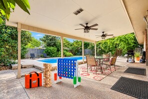 Área externa coberta com piscina, assentos e um jogo de Jenga.