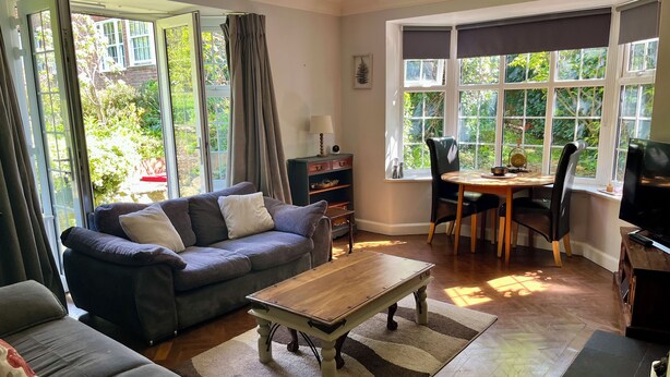 A living room with a sofa, a coffee table, a dining table with chairs, and large windows with curtains. - 10 min walk to York Minster & Station (York)