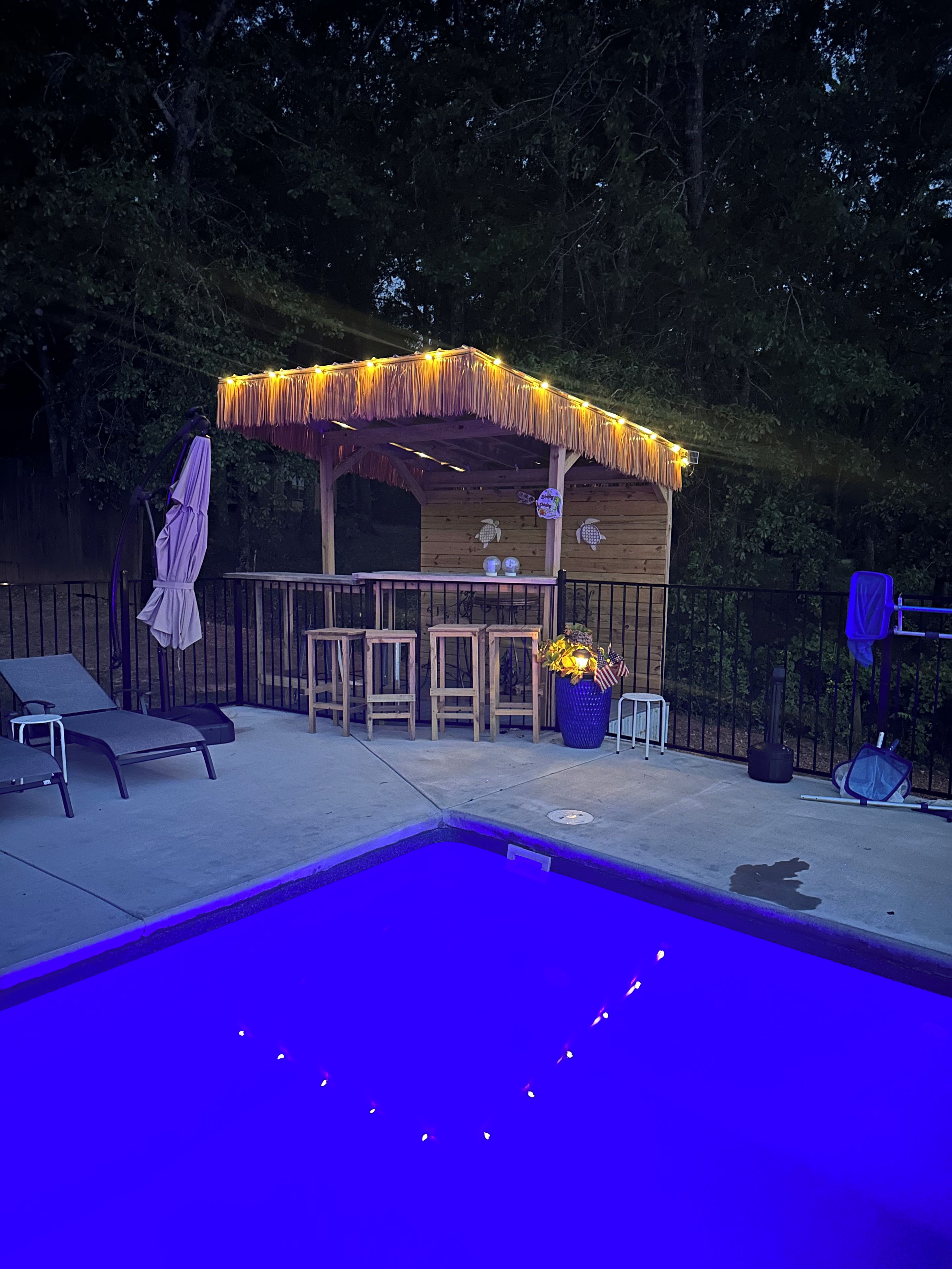 A poolside area with a tiki bar, lounge chairs, and a small pool.
