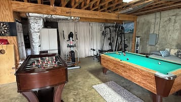 A recreational room with a foosball table, pool table, and exercise equipment.