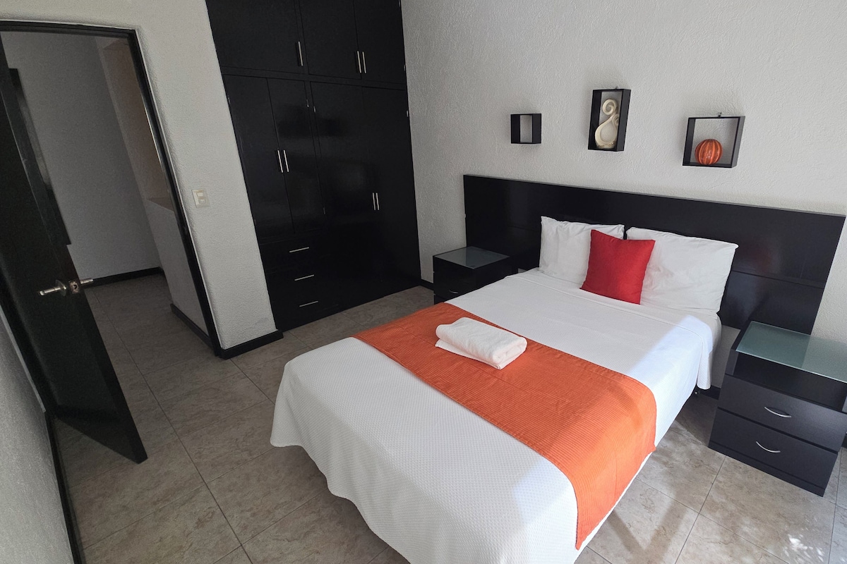 A hotel room with a bed, a nightstand, a wardrobe, and a door.