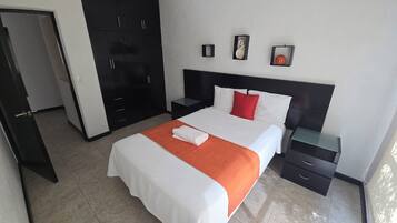 A hotel room with a bed, a nightstand, a wardrobe, and a door.