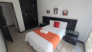 A hotel room with a bed, a nightstand, a wardrobe, and a door. - La reserva suites (Santiago de Querétaro)