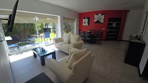 A living room with a sofa, a glass coffee table, and a dining area with chairs and a table. - La reserva suites (Santiago de Querétaro)