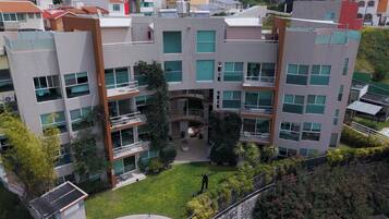 A multi-story residential building with balconies, a central courtyard, and surrounding greenery.