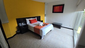 Habitació d'hotel amb un llit, taules de nit, una finestra i una obra d'art penjada a la paret.