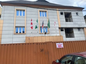 Un bâtiment doté de nombreuses fenêtres et d’un panneau indiquant que les voitures sont garées aux risques et périls de leurs propriétaires.