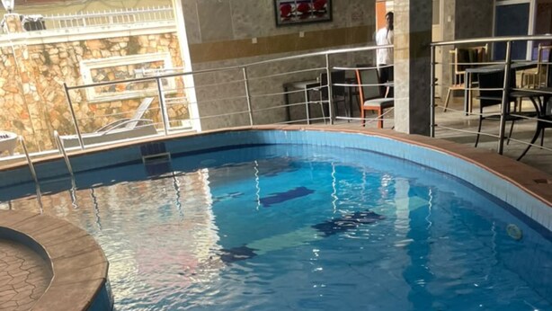 Una piscina interior con superficie de agua cristalina, rodeada por una solería de baldosas y barandillas metálicas.