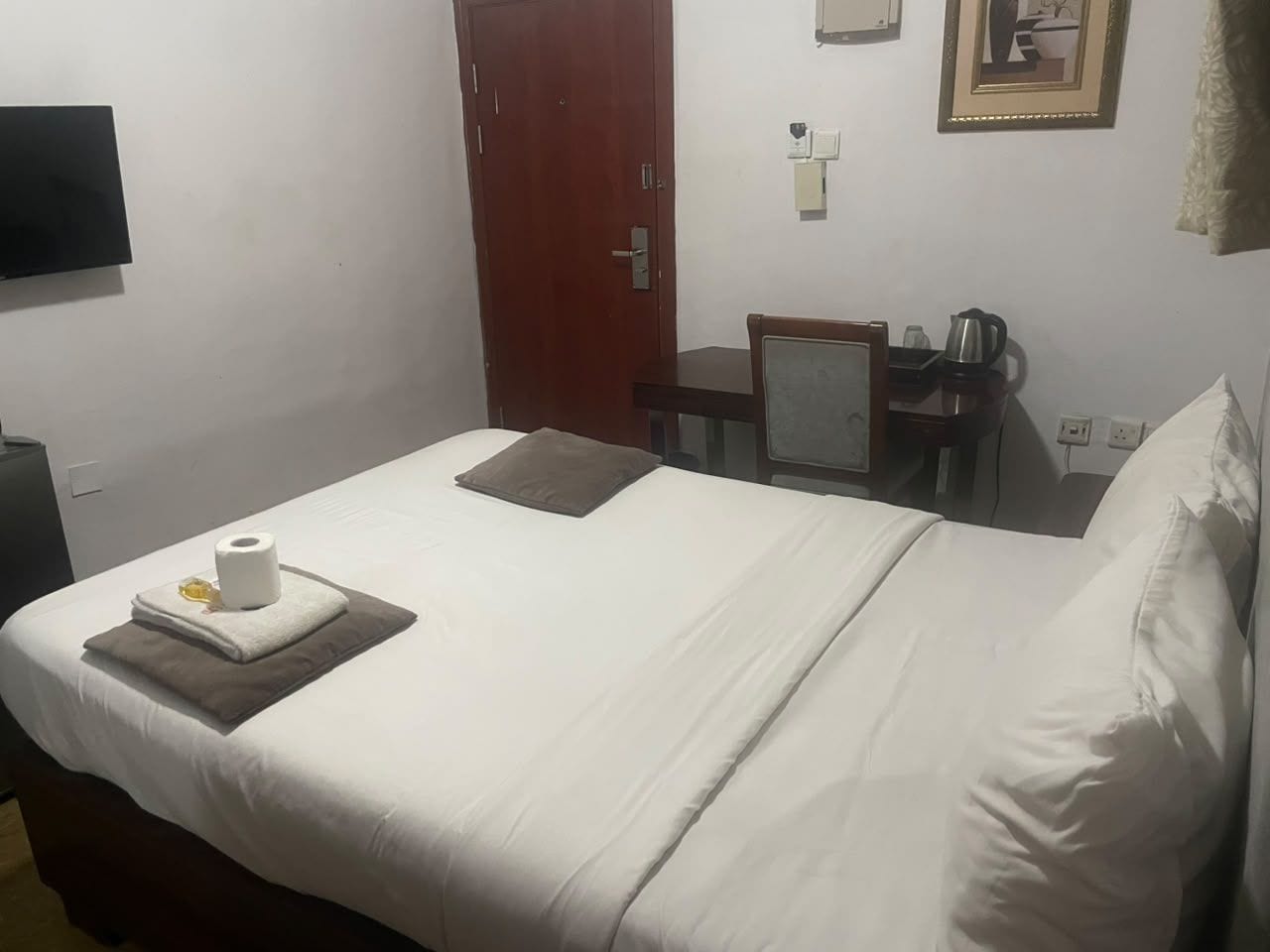 Een hotelkamer met een bed, een bureau, een stoel, een koffiezetapparaat en een televisie.