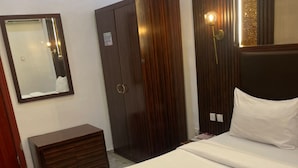 Una habitación de hotel con cama, armario, cómoda, espejo y lámpara de pared.